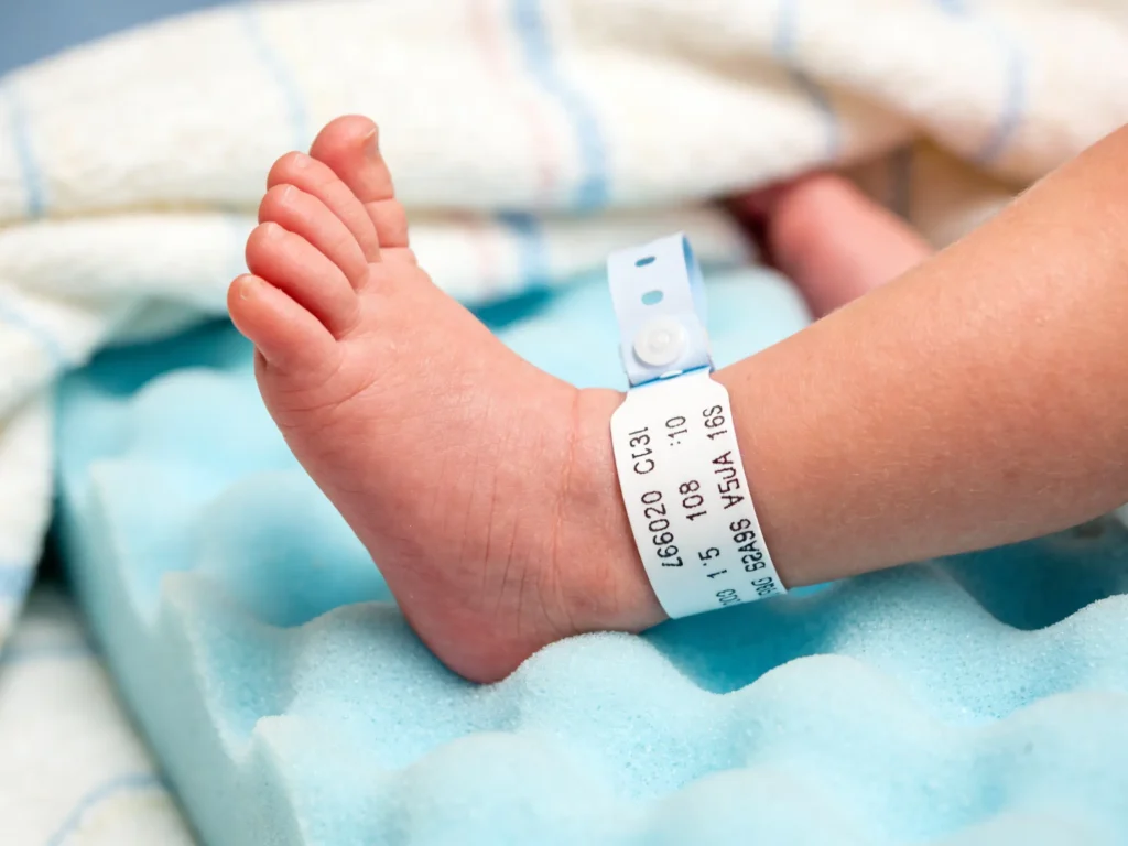 Ultra-soft hypoallergenic foam NICU wristband on a newborn baby's ankle for safe neonatal identification.